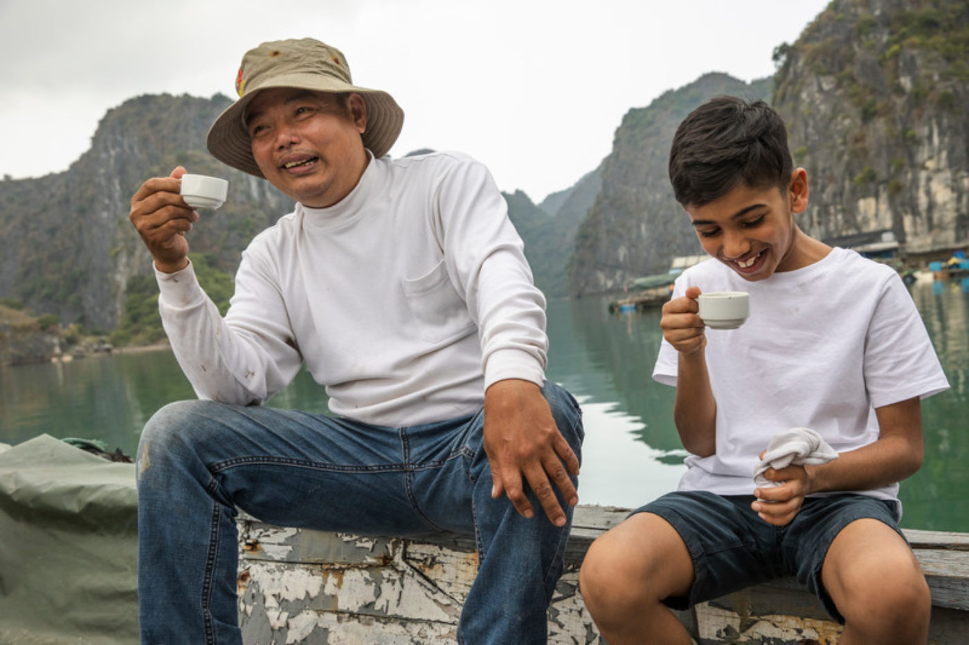 Vietnam Lan Ha Bay Floating Fish Farm Local Man Boy Laughing Drinking Tea Interaction large Credit G Adventures